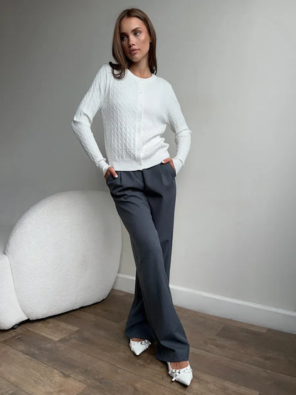 Model wearing an Ivory Cardigan by Lauven, showcasing a lightweight cable knit sweater and stylish gray pants.