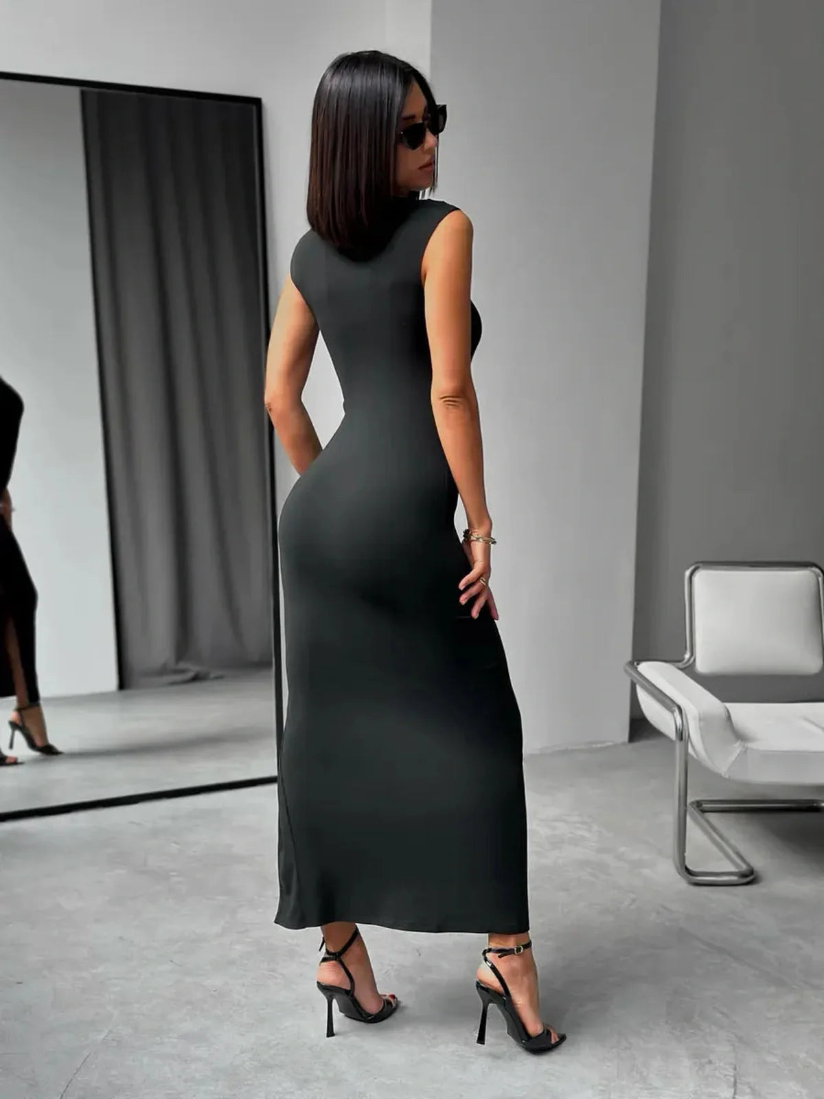 Model showcasing the Sculpted Charm Maxi Dress, a sleek black design with a body-hugging fit and square neckline.