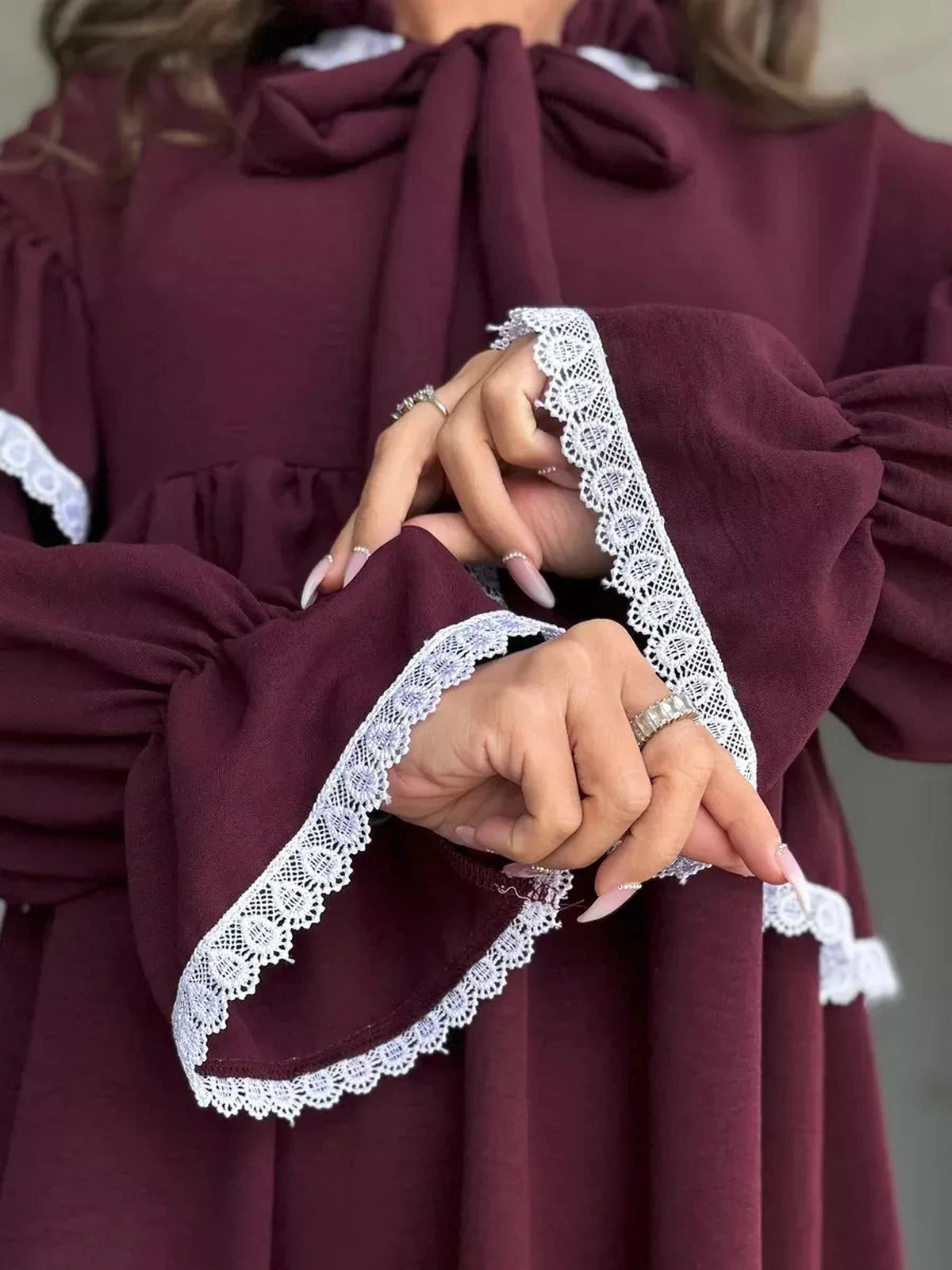 Close-up of the Marina Mini Dress by Lauven, featuring delicate lace trim and ruffle details on burgundy sleeves.