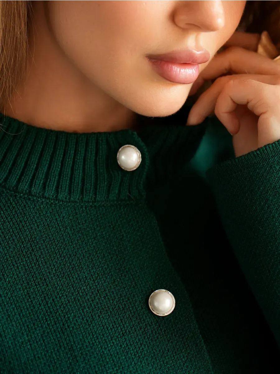 Close-up of a woman wearing the Verdant Cardigan by Lauven featuring pearl button closure in rich emerald green.