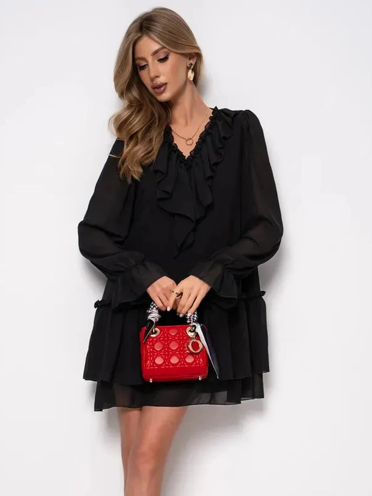 Noirelle Mini Dress by Lauven showcased in black chiffon with ruffled layers, paired with a red handbag.