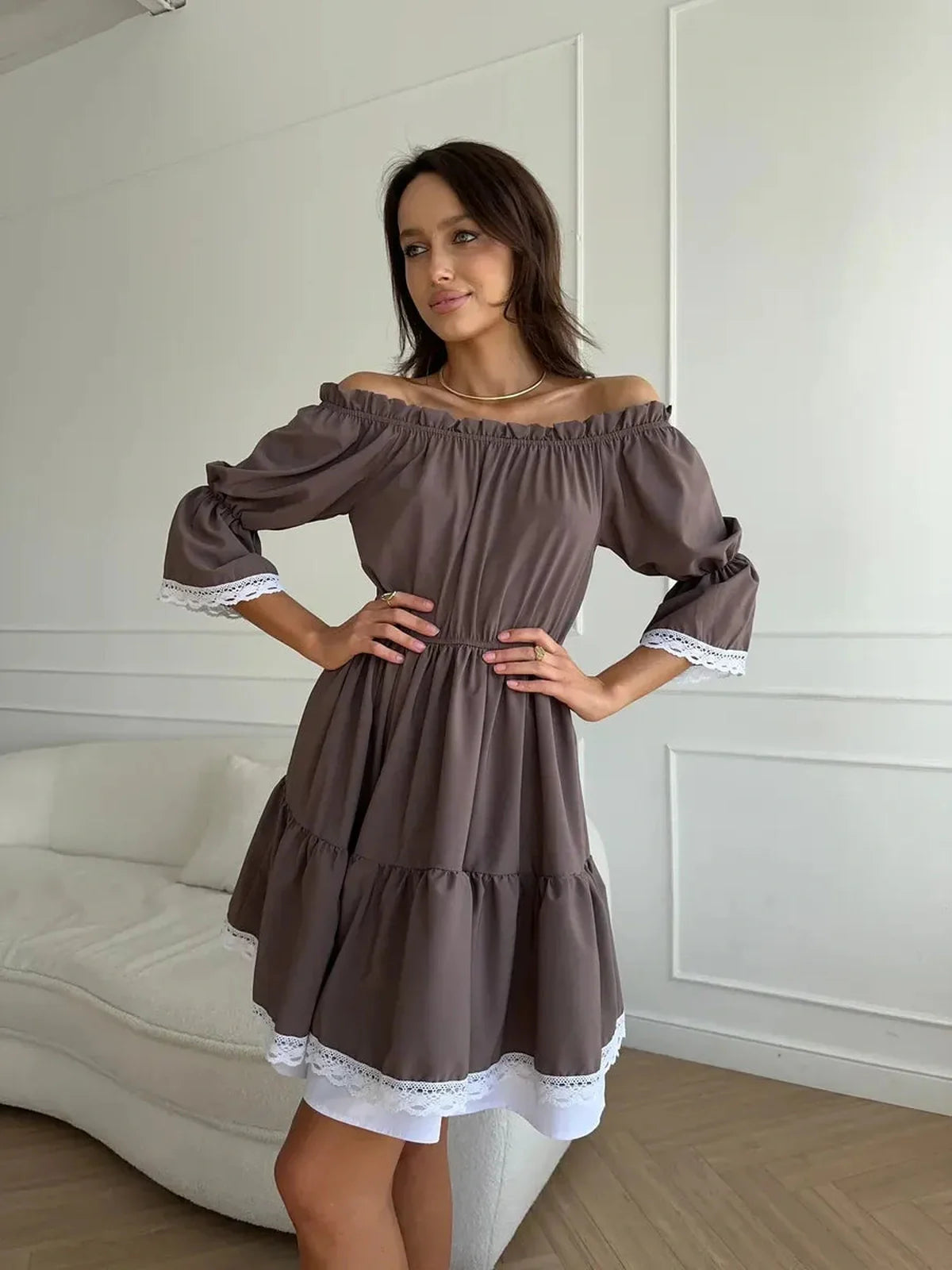 Model wearing Mocha Muse off-shoulder mini dress in mocha brown with white lace trim, showcasing summer elegance.