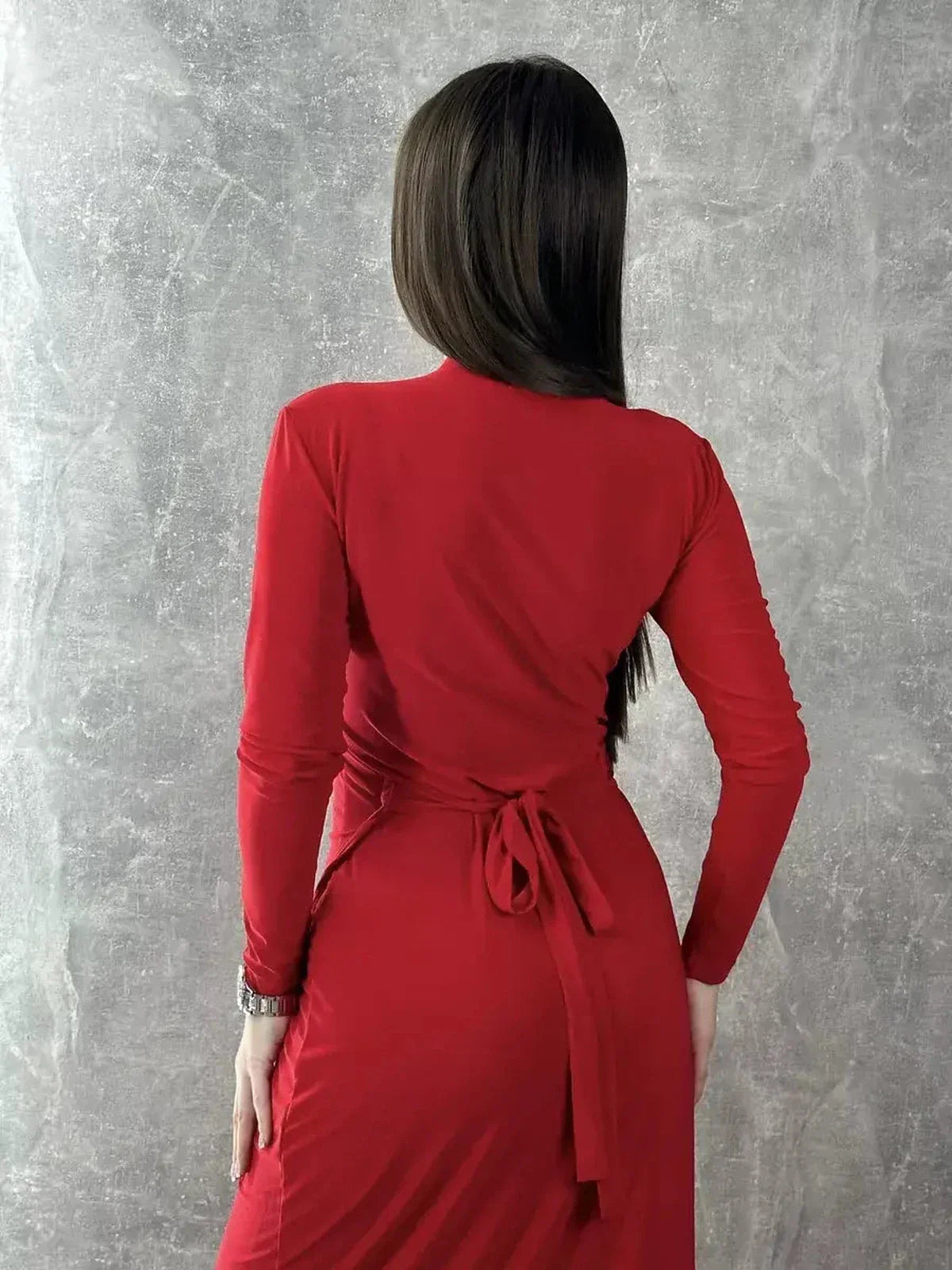 Back view of a model wearing a long sleeve red maxi dress with a tie waist, highlighting its elegant drape.