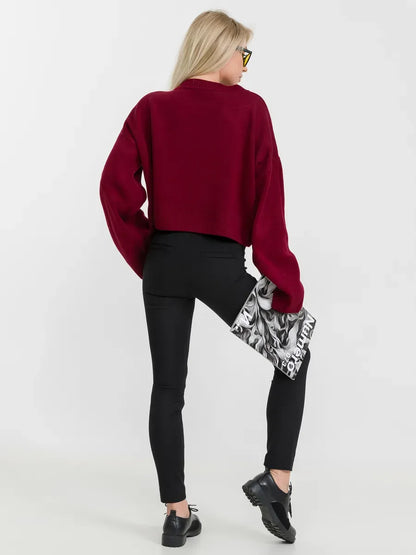 Back view of a woman wearing a burgundy Marbella Sweater by Lauven, styled with black pants and a chic clutch.