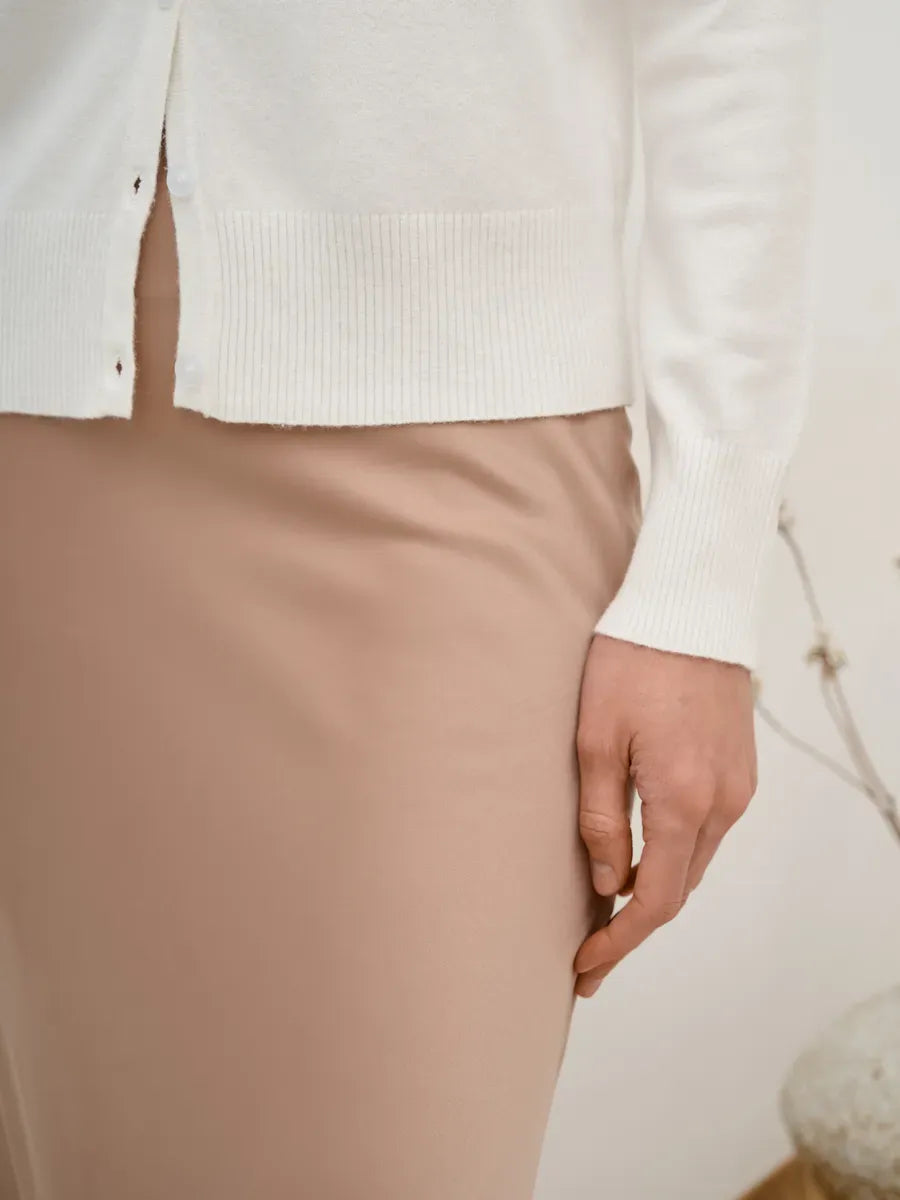 Close-up of a model wearing the Selene Cardigan by Lauven, showcasing elegant white knitwear and button closure.