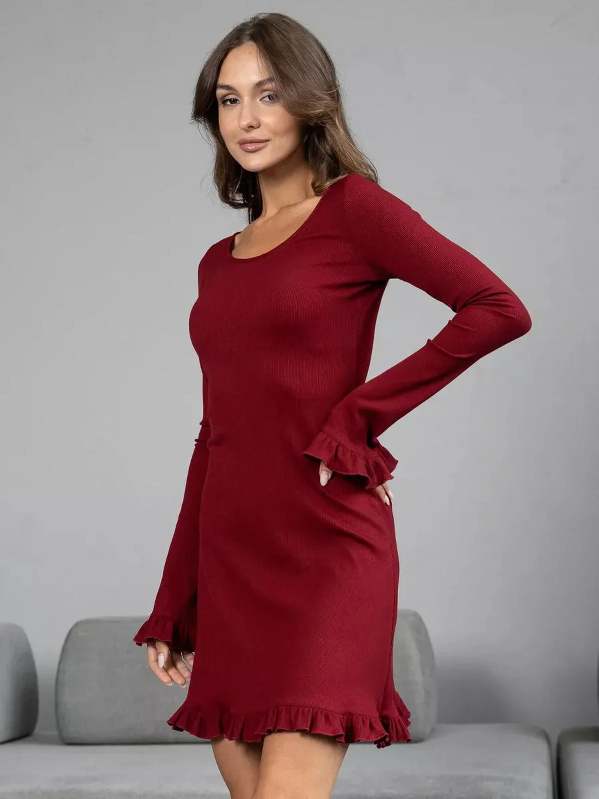 Model wearing a sultry crimson red long sleeve dress with ruffled cuffs and hem, showcasing a flattering silhouette.