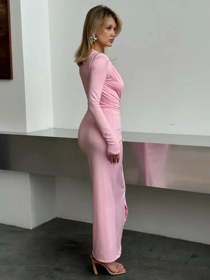 Model showcasing the Blush Muse Maxi Dress in soft pink, featuring long sleeves and a plunging neckline.