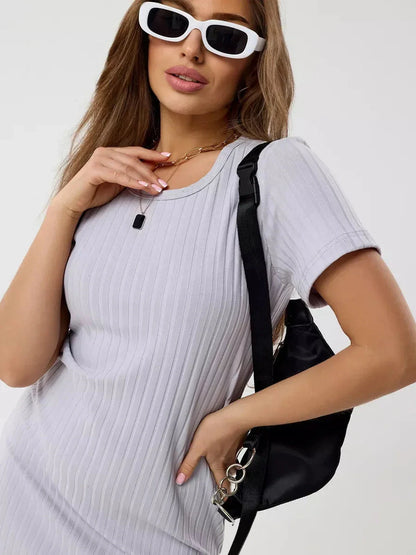 A stylish woman wearing a ribbed mini dress with short sleeves, sunglasses, and a black bag, showcasing casual summer fashion.