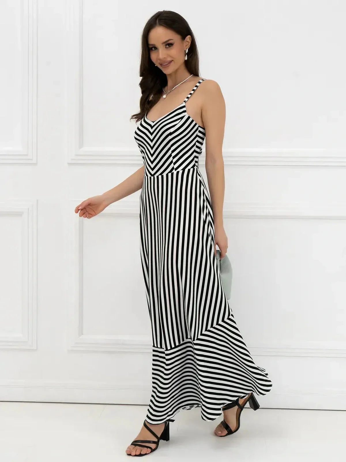 Model wearing a black and white striped Maxi Dress Mirage Lines, showcasing its fitted bodice and flowing A-line silhouette.