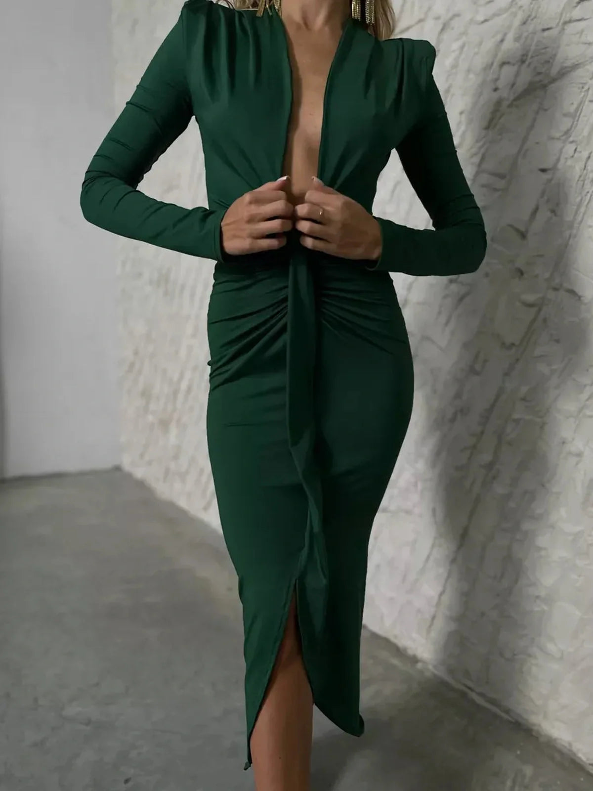 Model wearing a deep emerald Sculpted Drape Maxi Dress featuring a plunging neckline and bold draping.