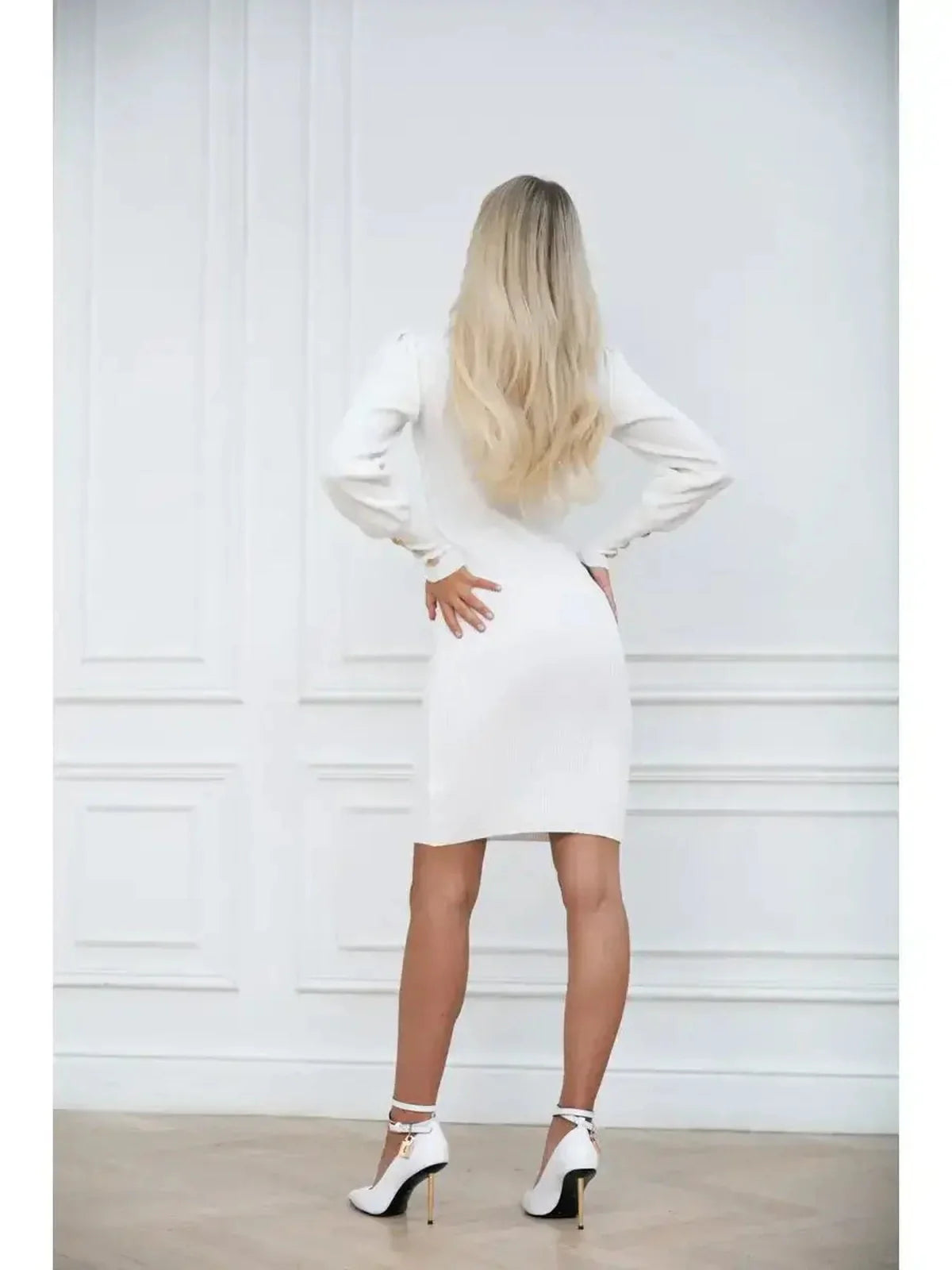 Back view of a woman in an ivory curve mini dress with voluminous sleeves and high-fashion heels.