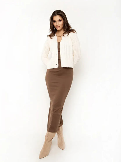 Model wearing Isola Cardigan by Lauven, a cropped cream knit cardigan paired with a brown dress.