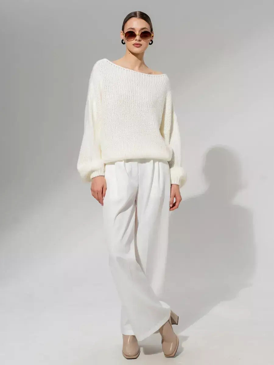 Model wearing an Ivory Sweater by Lauven, oversized off-shoulder knit in white, paired with wide-leg trousers.
