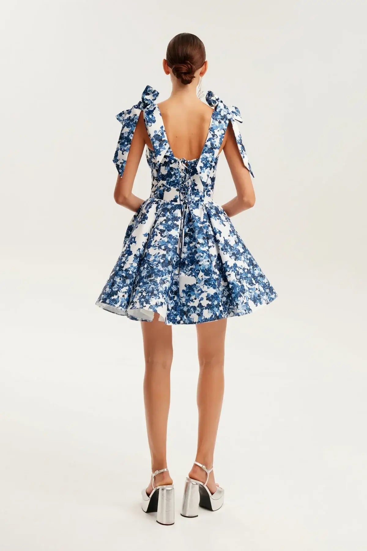Back view of a blue floral mini dress with bow details, perfect for summer occasions and bridal events.
