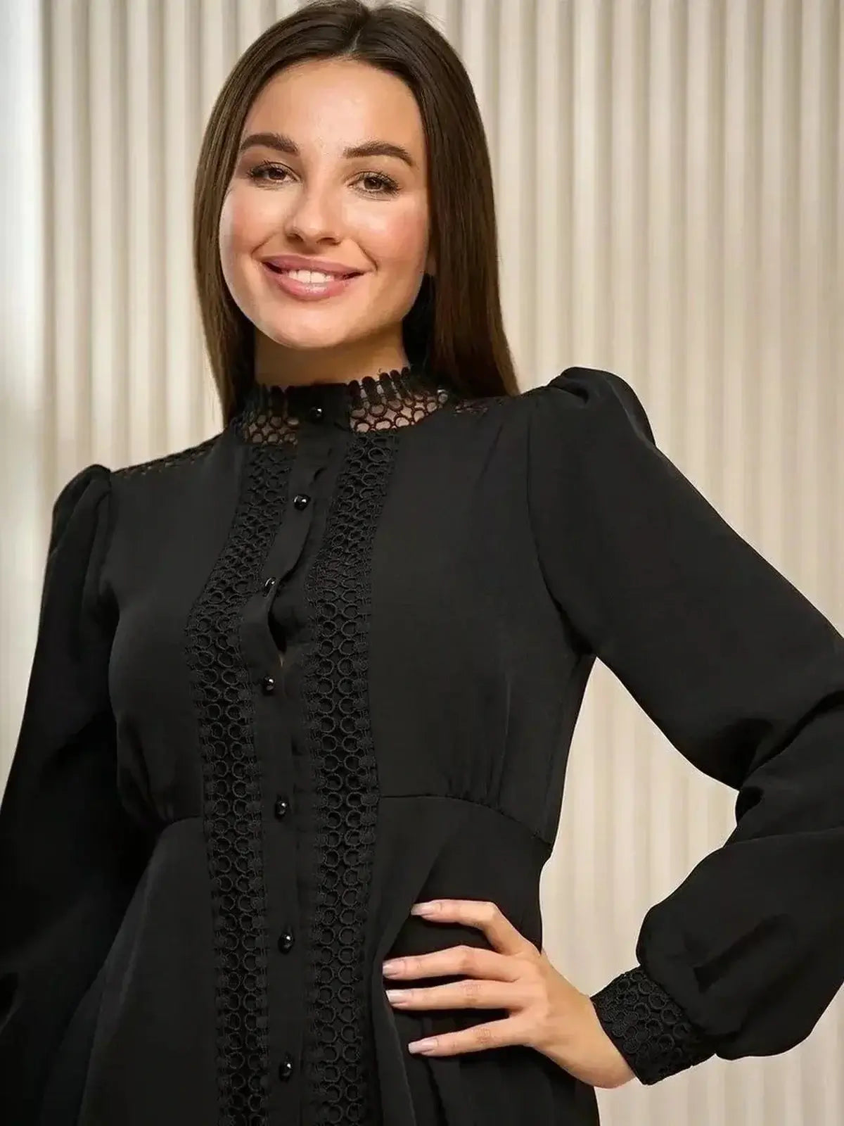 Stylish woman modeling a black mini dress with lace trim and a high collar for formal events.