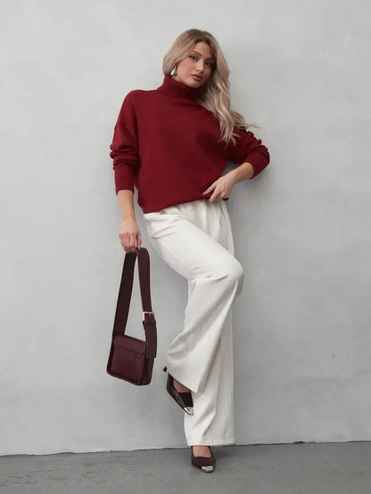 Arden Sweater by Lauven – Burgundy turtleneck knitwear worn with white pants for a chic autumn look.
