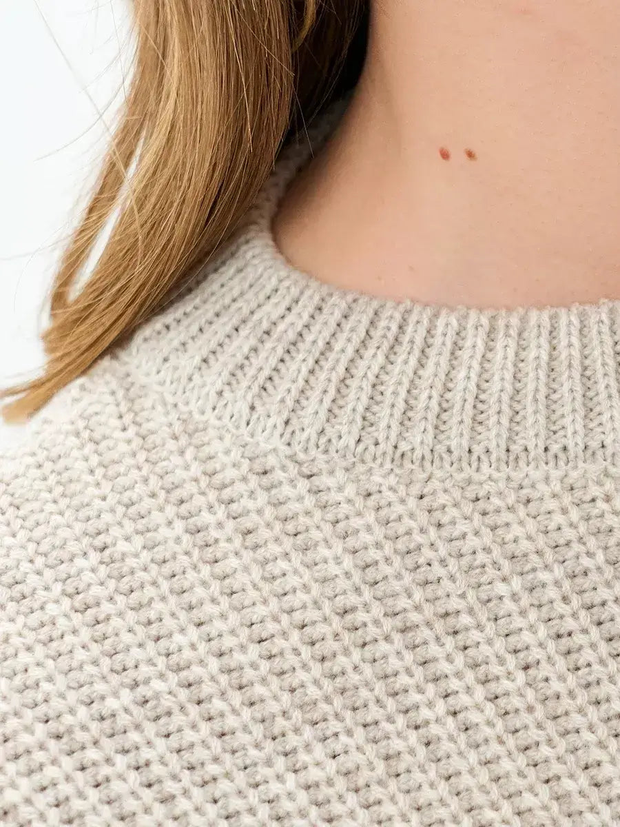 Close-up of the collar detail of the Astra Sweater by Lauven in light beige knit fabric.