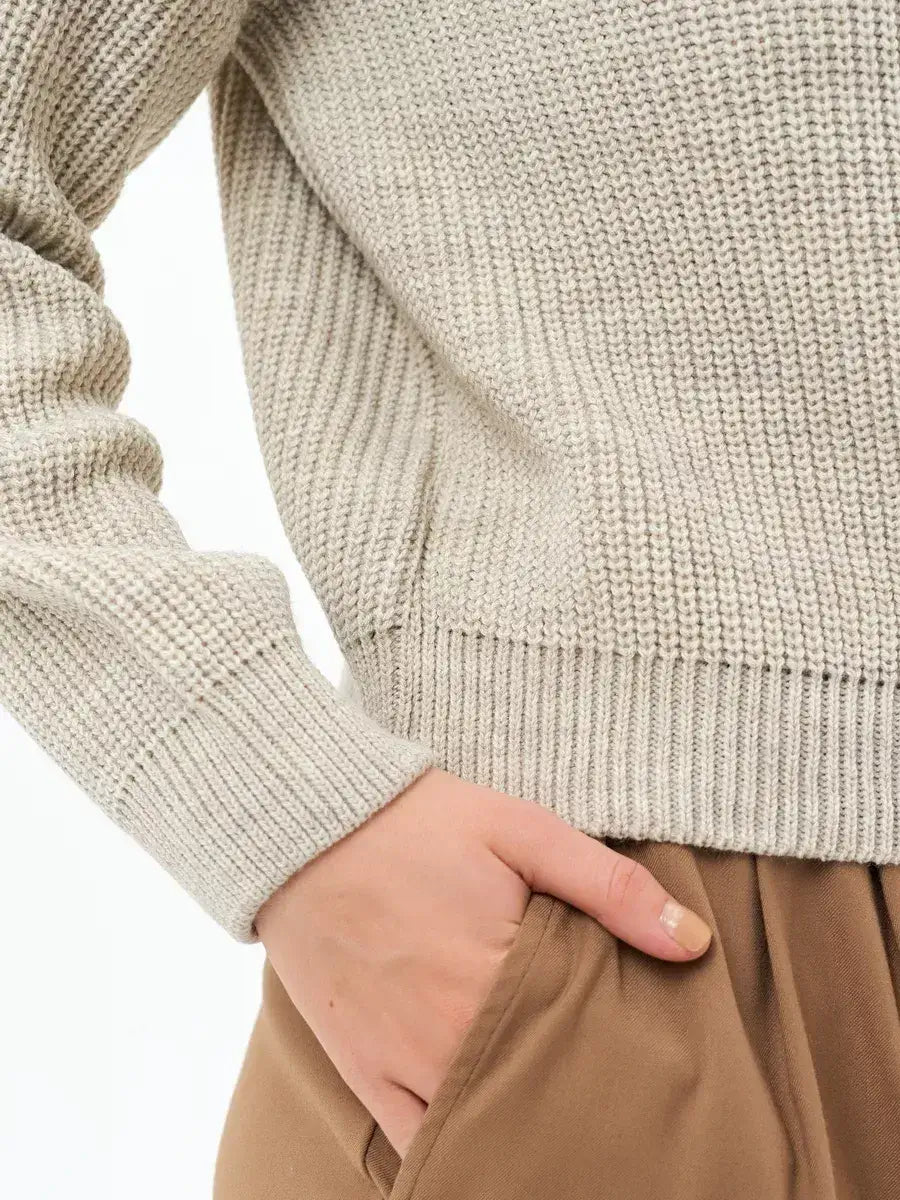 Detail of the Astra Sweater by Lauven, showcasing the soft rib-knit texture and elegant light beige color.