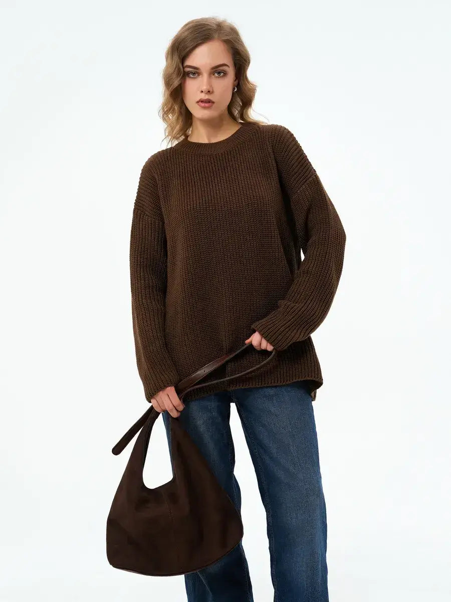 Model wearing the Atlas Sweater by Lauven, an oversized knit in rich brown, paired with a brown handbag.