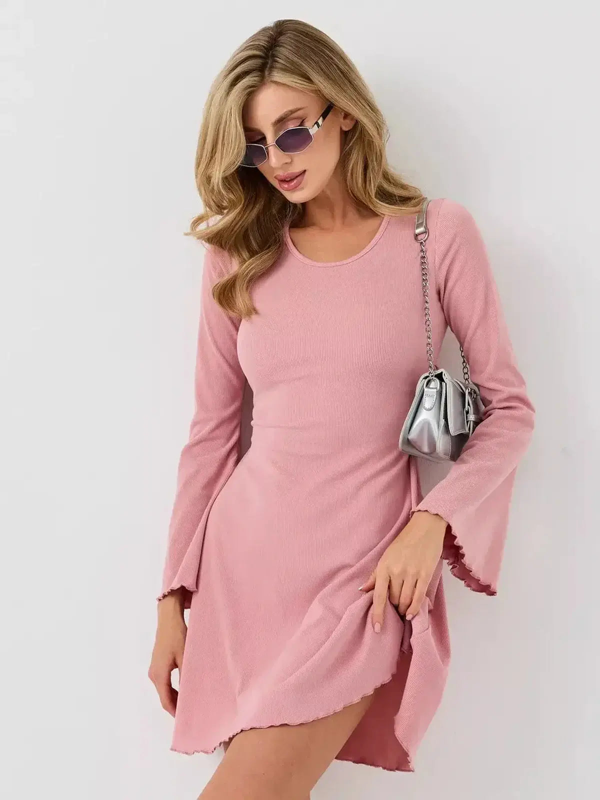 Model wearing the Blush Flare mini dress by Lauven, showcasing its soft pink hue and flared bell sleeves.