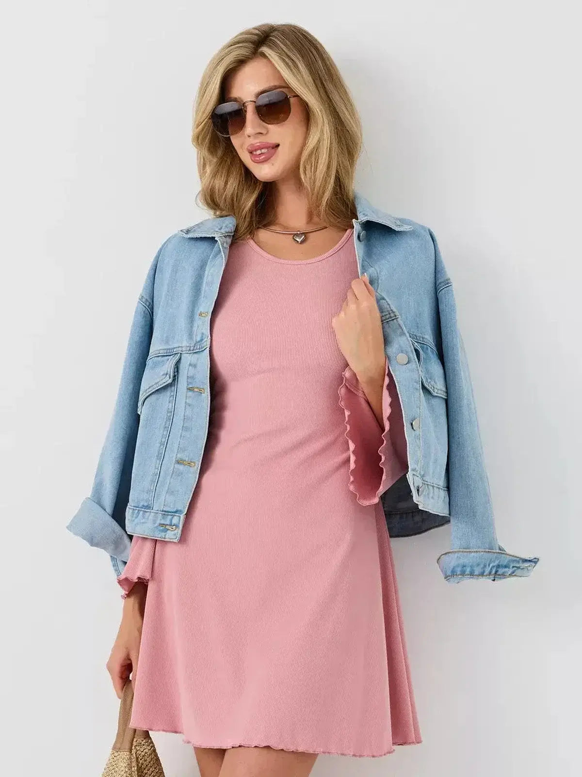 Model wearing the Blush Flare dress by Lauven, styled with a denim jacket and sunglasses for a chic look.