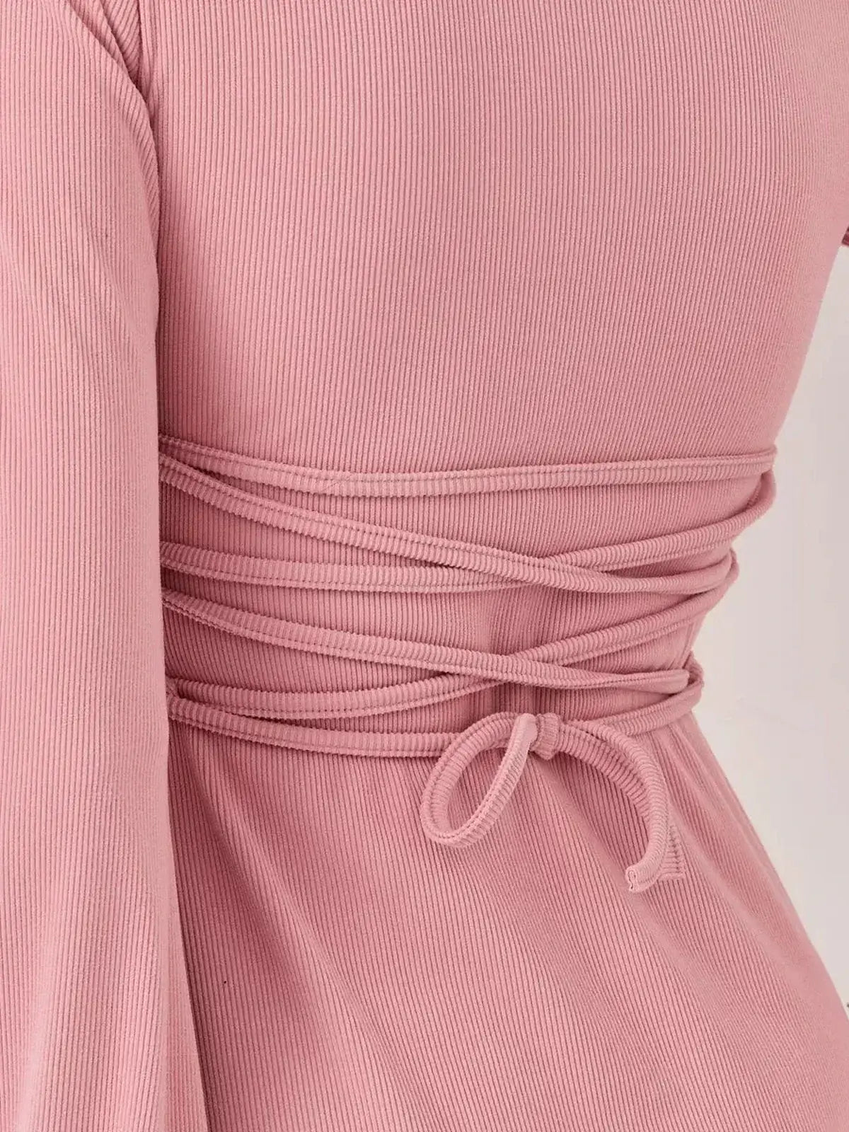 Back view of the Blush Flare mini dress by Lauven, showcasing the soft pink ribbed fabric and stylish tie detail.