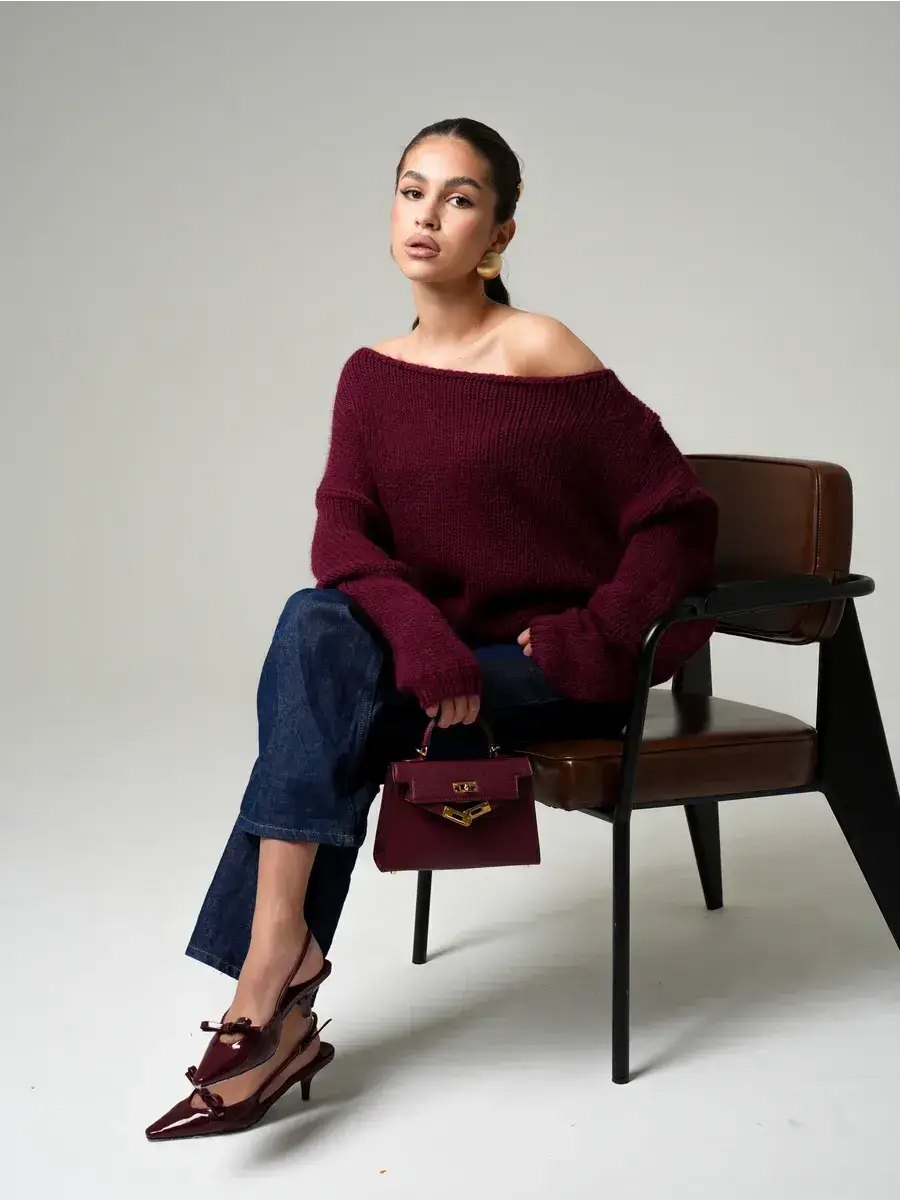 Model wearing Bordeaux Sweater by Lauven, an oversized off-shoulder knit in deep wine, styled with denim and chic accessories.