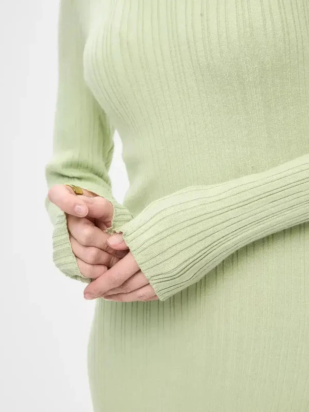 Close-up of hands wearing the long sleeves of the Celery Luxe Maxi Dress by Lauven, showcasing the ribbed knit texture.