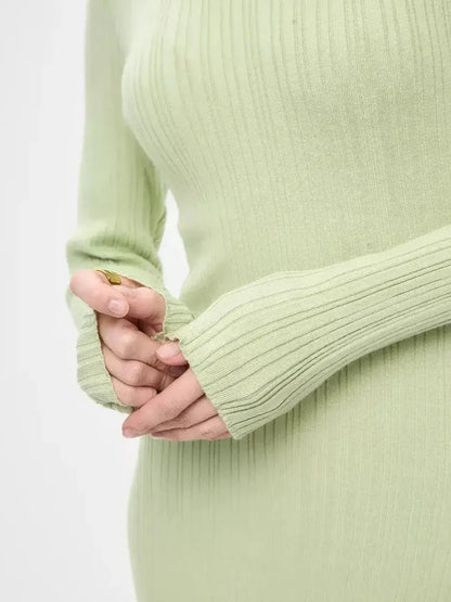 Close-up of hands wearing the long sleeves of the Celery Luxe Maxi Dress by Lauven, showcasing the ribbed knit texture.