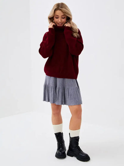 Model wearing a cozy Crimson Pullover by Lauven with a grey skirt and boots, showcasing a stylish winter look.