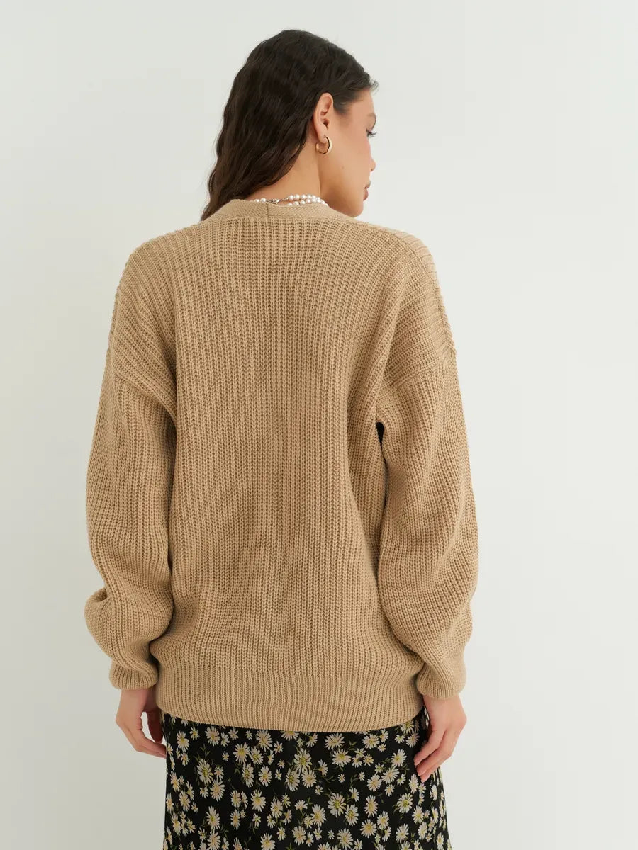 Back view of a woman wearing the Dune Cardigan by Lauven in dark beige, showcasing its oversized and cozy design.