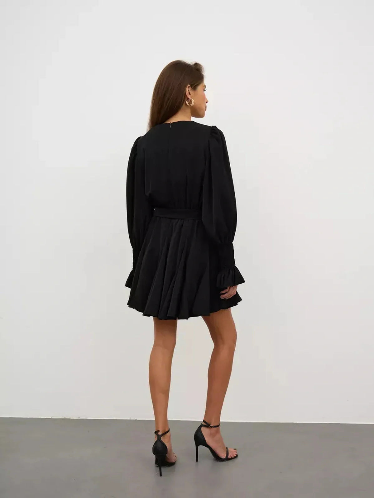 Back view of a woman wearing the Lauven Eclipse Mini Dress, featuring long sleeves and a ruffled hem.