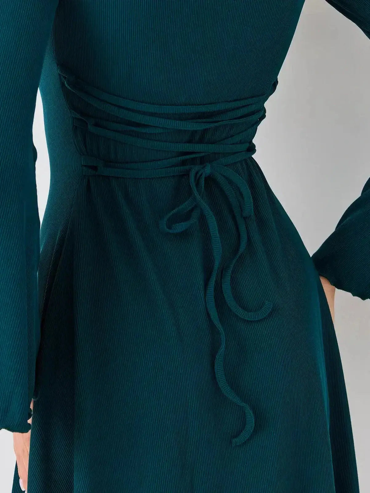 Back detail of Emerald Whisper mini dress by Lauven, featuring a stylish tied waist for a flattering fit.
