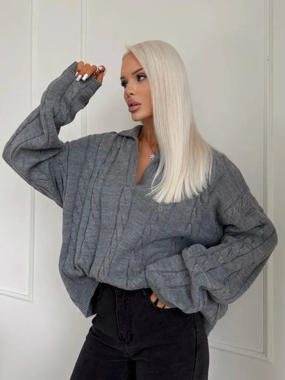 Model wearing a Graphite Sweater by Lauven, showcasing its oversized cable knit design and V-neckline.