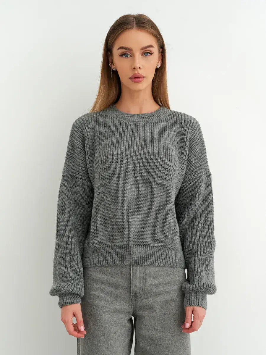 Woman wearing a grey oversized knit Vega Sweater by Lauven, showcasing a modern minimalist style.