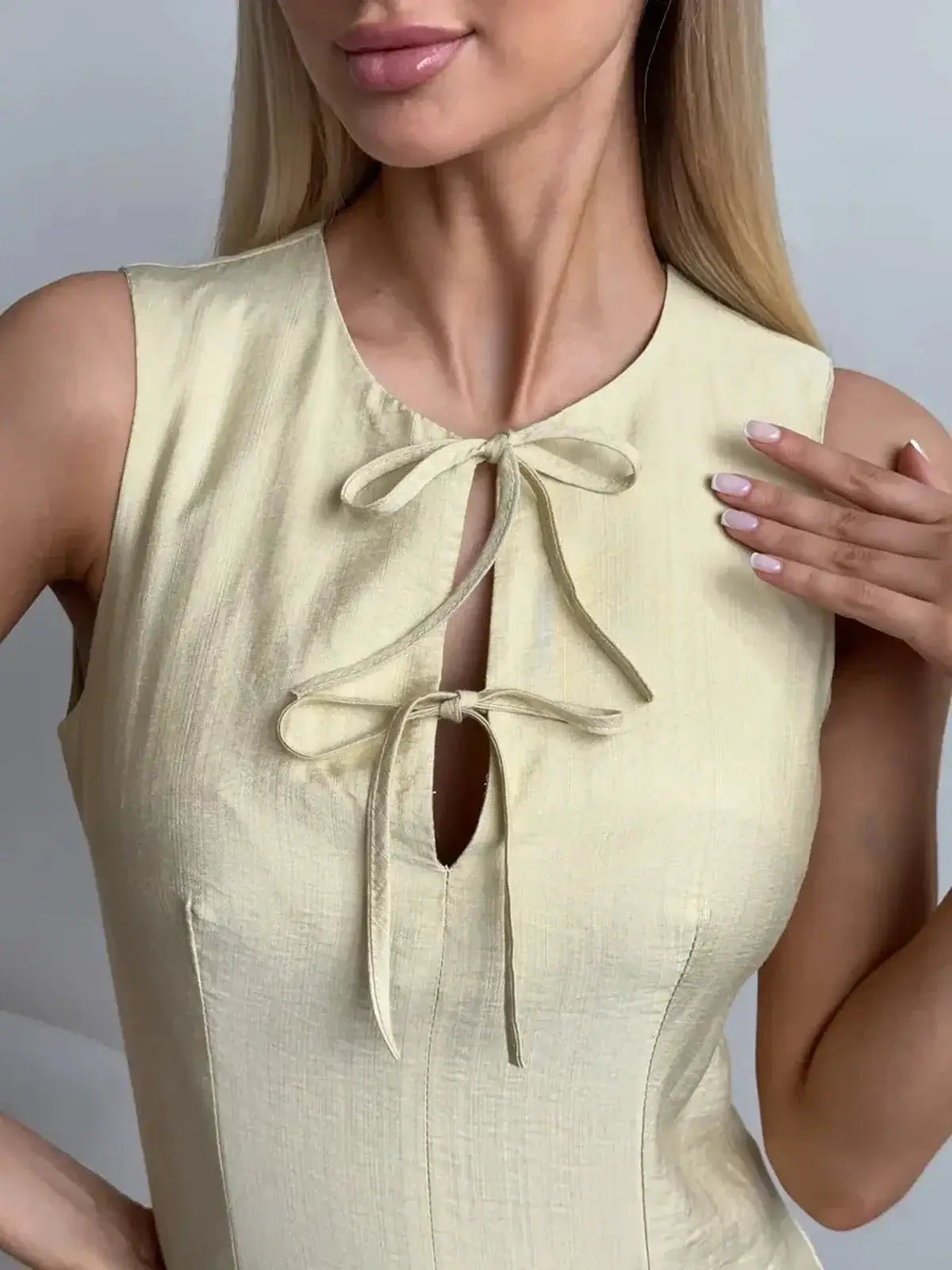 Close-up of a woman wearing a sleeveless Lemon Flare mini dress with tie-front closures, perfect for summer outings.