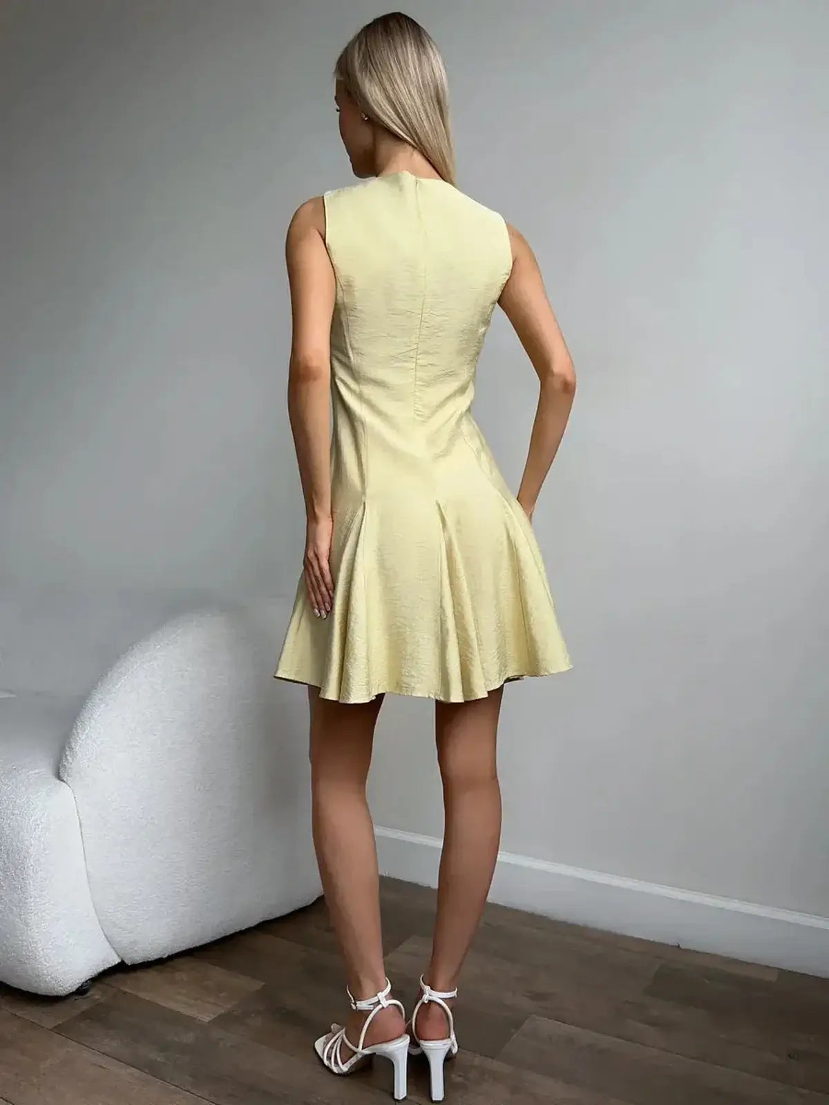 Back view of a woman wearing a sleeveless Lemon Flare dress, perfect for summer, weddings, and casual outings.