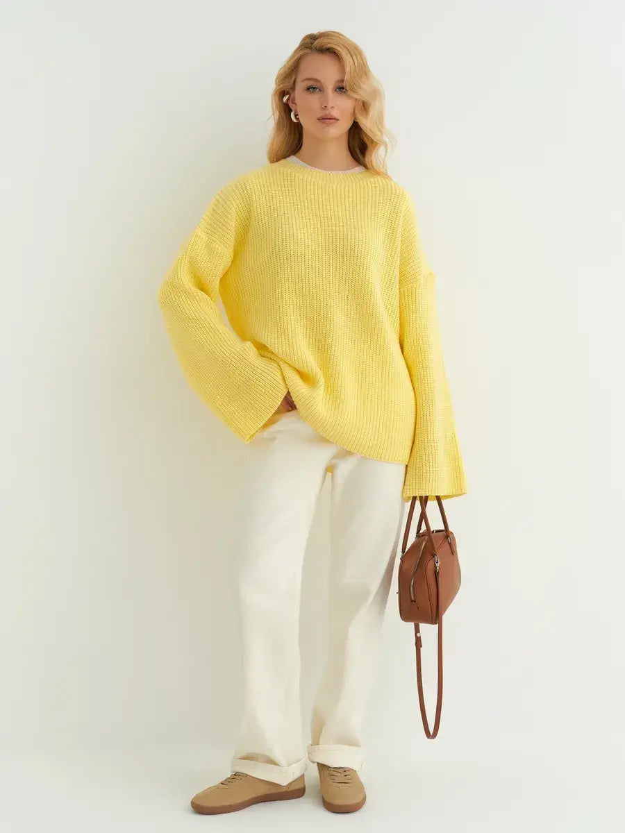 Woman wearing a Lemonade Sweater from Lauven in soft lemon yellow, styled with white pants and a brown handbag.