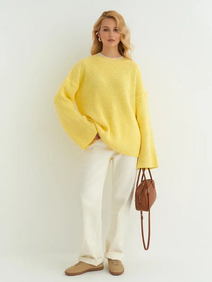 Woman wearing a Lemonade Sweater from Lauven in soft lemon yellow, styled with white pants and a brown handbag.