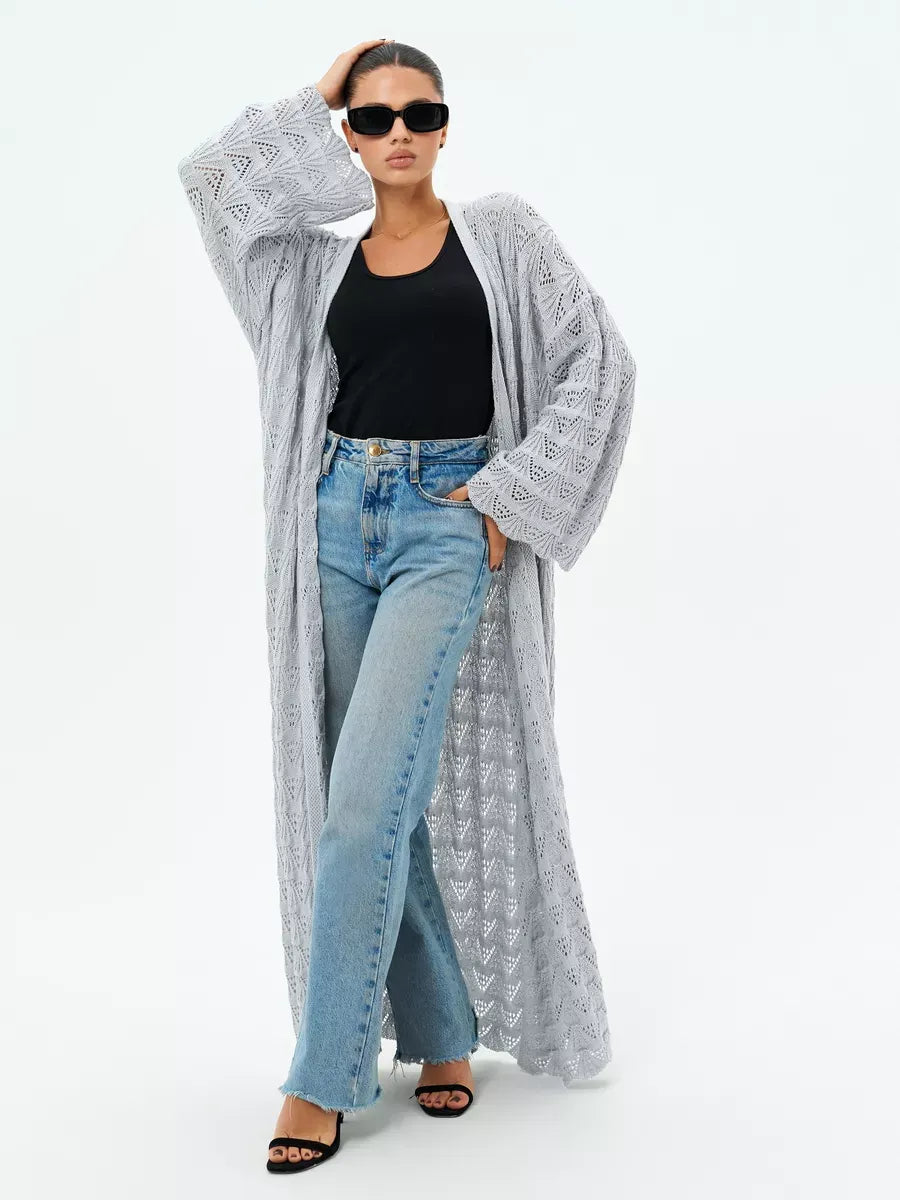 Woman wearing a lightweight Mist Cardigan by Lauven with openwork design over a black top and light blue jeans.