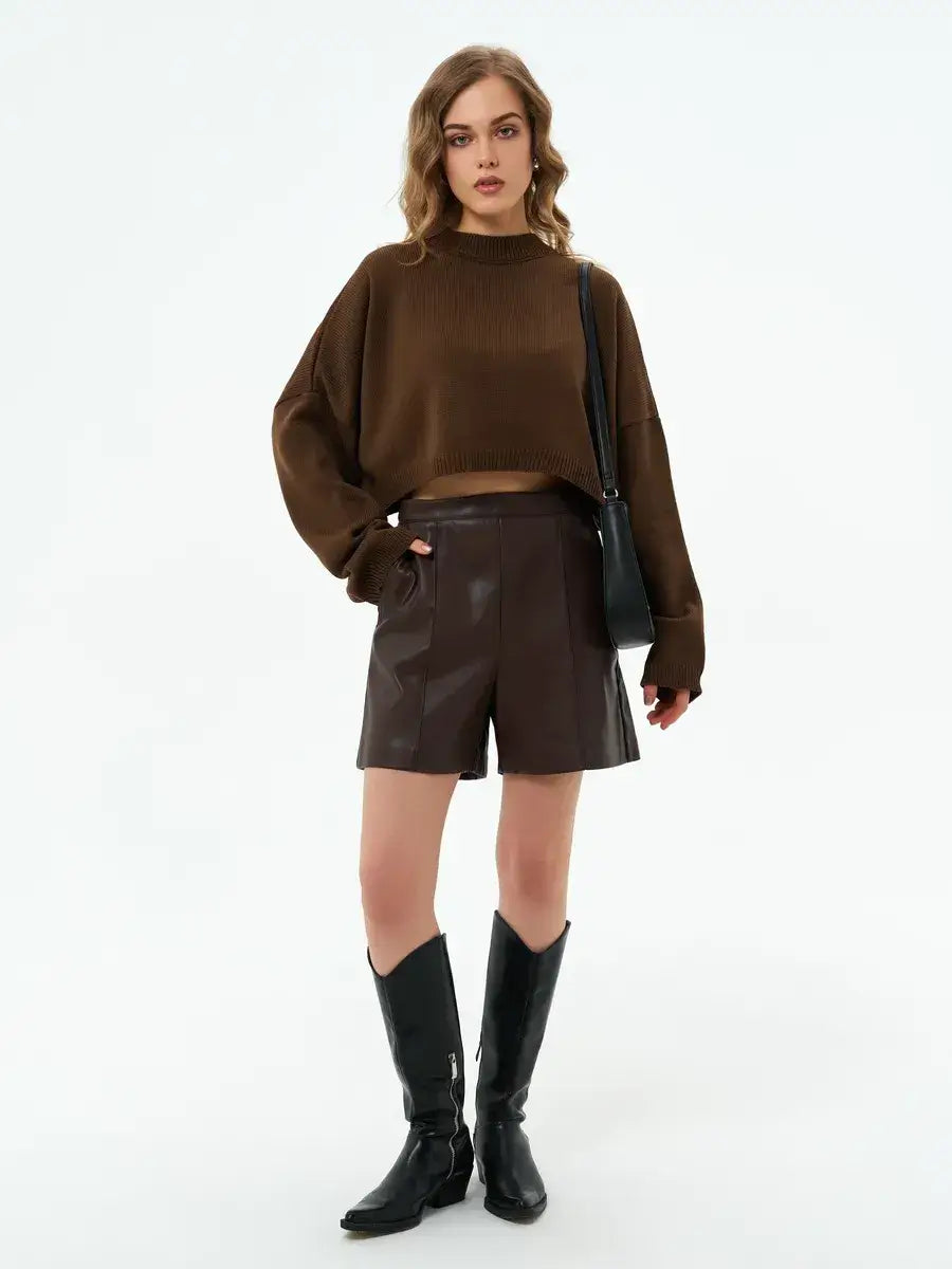 Model wearing the Mocha Sweater by Lauven with brown shorts and boots, showcasing a stylish oversized cropped look.