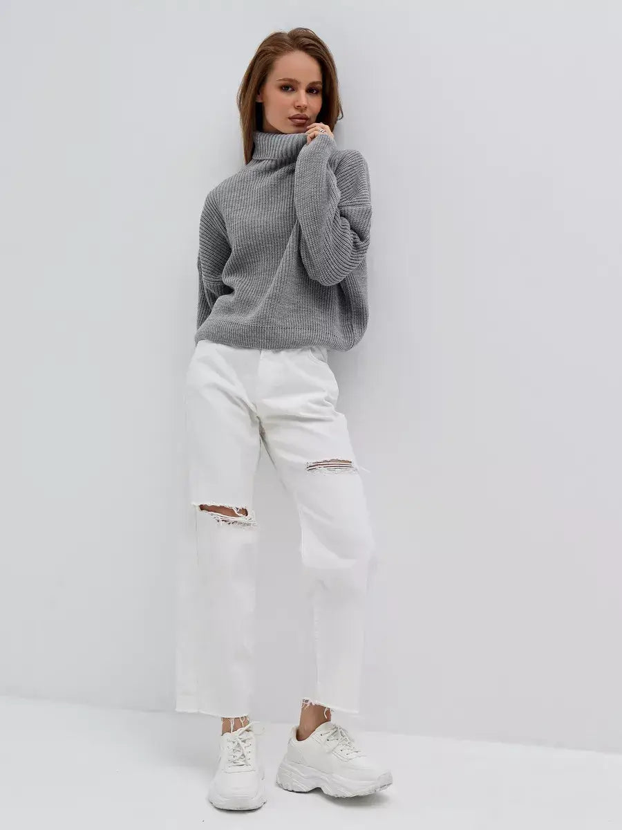 Woman in oversized light gray Nimbus Pullover by Lauven, styled with white ripped jeans and casual sneakers.