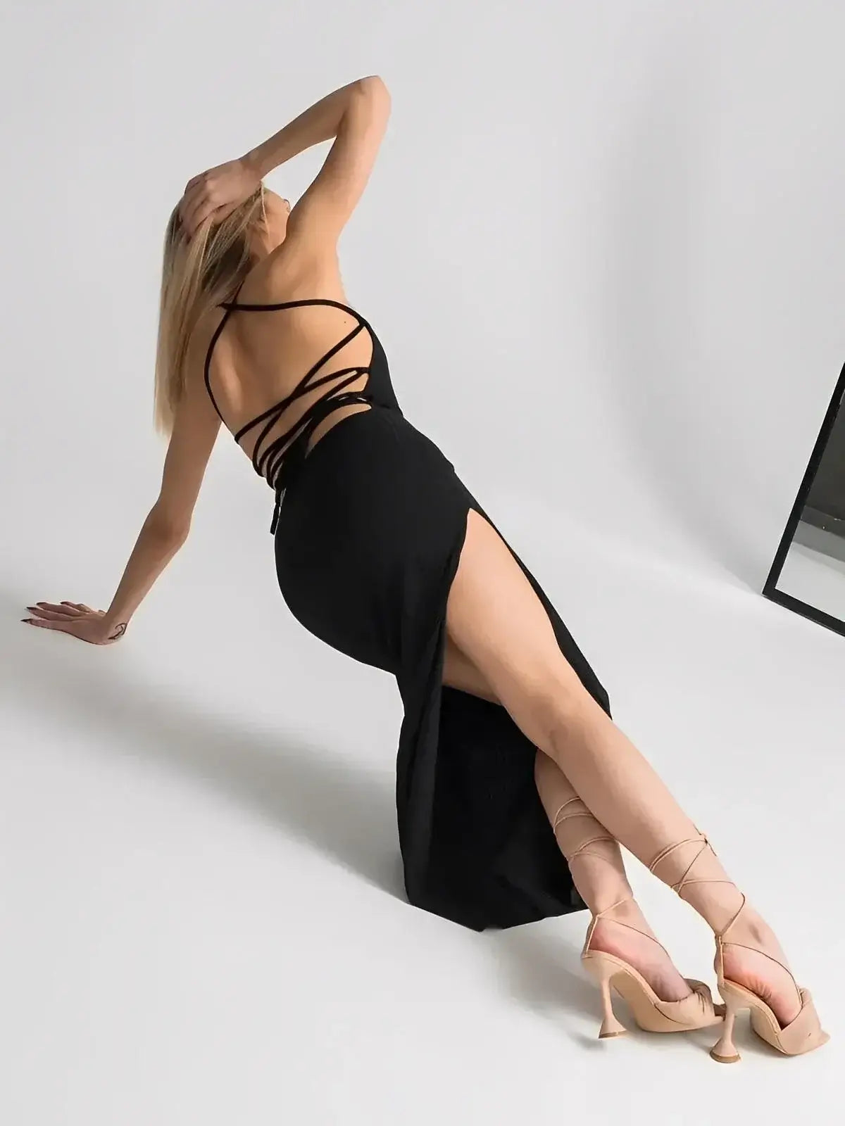 Model showcasing the Noir Lace Midi Dress by Lauven, featuring a dramatic open back and thigh-high slit.