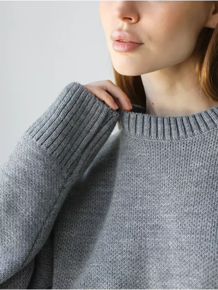 Close-up of a woman wearing the Nova Pullover by Lauven, showcasing the soft gray fabric and oversized cuffs.