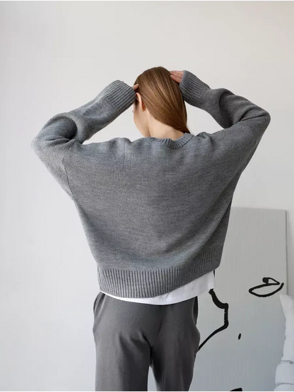 Back view of a model wearing the Nova Pullover, an oversized cropped women's sweater by Lauven in silver-gray.