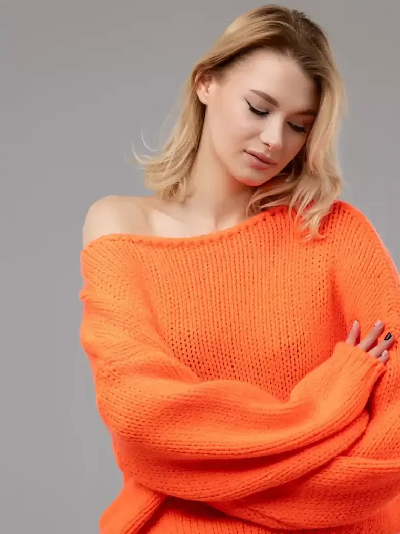Woman wearing the Nova Sweater by Lauven, an oversized off-shoulder knit in vibrant neon orange.