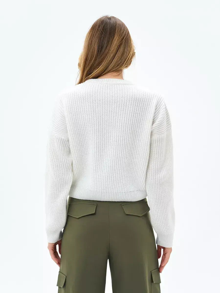 Back view of a woman wearing the Nova Sweater by Lauven, showcasing its oversized knit and cropped design.
