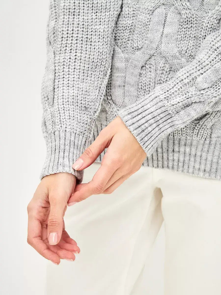 Close-up of hands adjusting the cuffs of the Osiris Sweater by Lauven in soft gray melange, showcasing cable knit details.