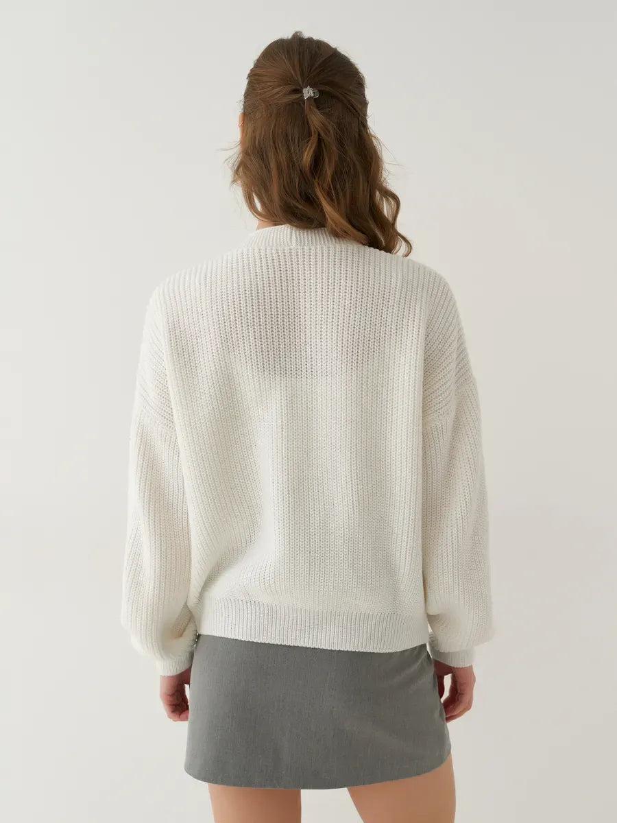 Back view of a woman wearing a Pearl Cardigan by Lauven, showcasing the oversized white knit design.