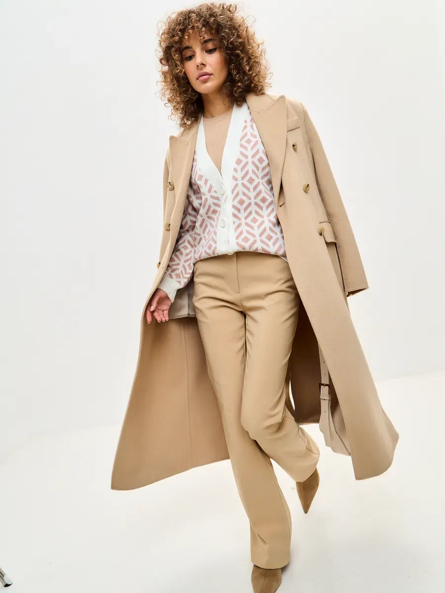 Model showcasing a stylish outfit featuring a Powder Cardigan by Lauven, paired with beige trousers and a chic coat.